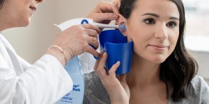 Patient receiving ear irrigation from physician.